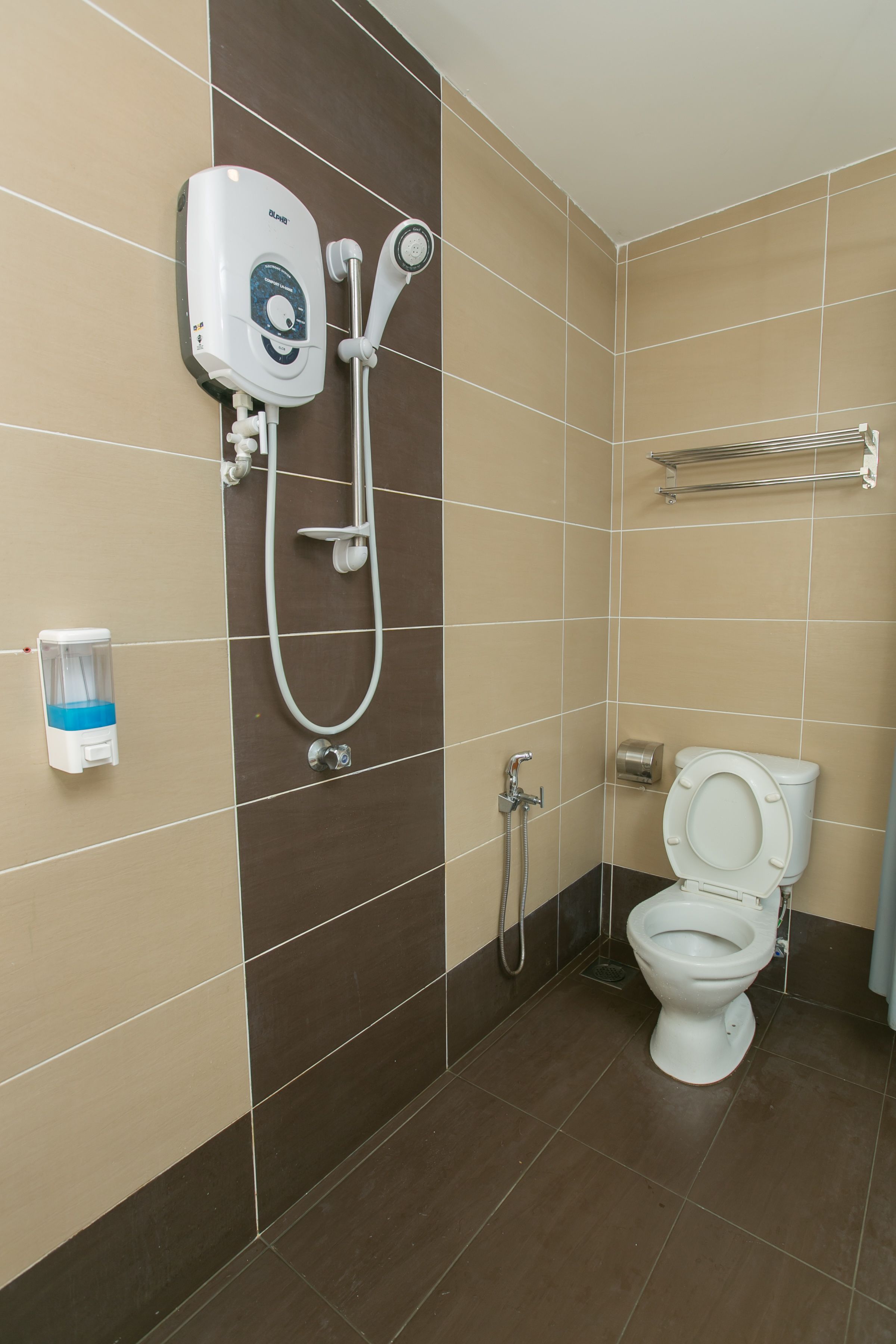 A bathroom with a toilet, a shower unit, and a hand dryer.