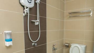 A bathroom with a toilet, a shower unit, and a hand dryer.
