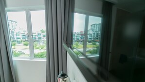 Ein Zimmer mit einem großen Fenster, Vorhängen und einem Wasserkocher auf der Fensterbank.