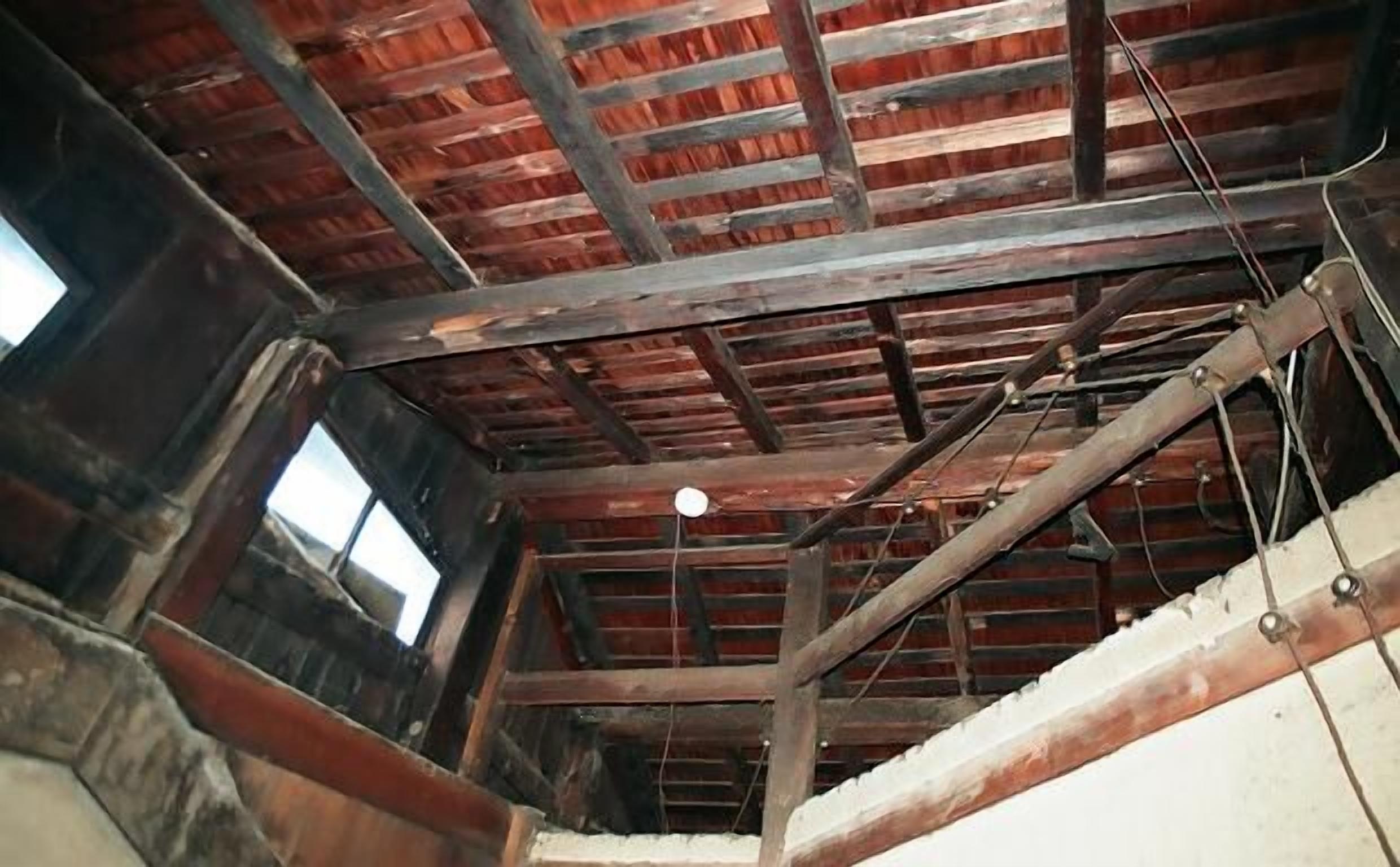 A room with exposed wooden beams and a visible ceiling light fixture.