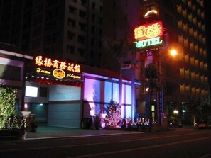 A hotel with illuminated signage, a large windowed facade, and a Christmas tree decoration. - Yuan Chyau Motel (Taichung)