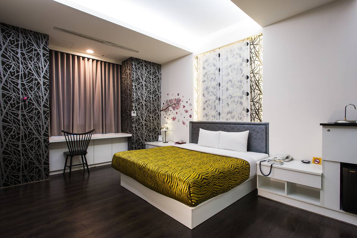 Habitació d'hotel moderna amb un llit gran, un escriptori i una cadira.