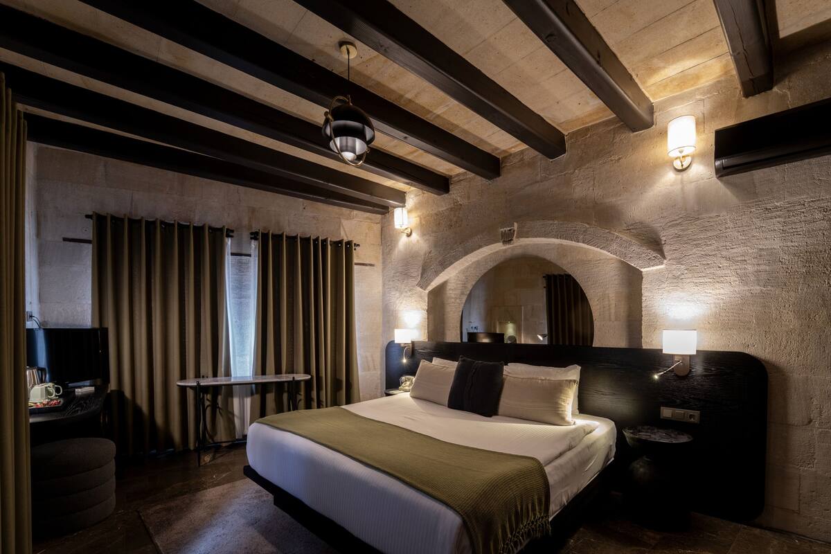 Una camera d'albergo con un letto grande, un tavolino, una televisione e un bagno.