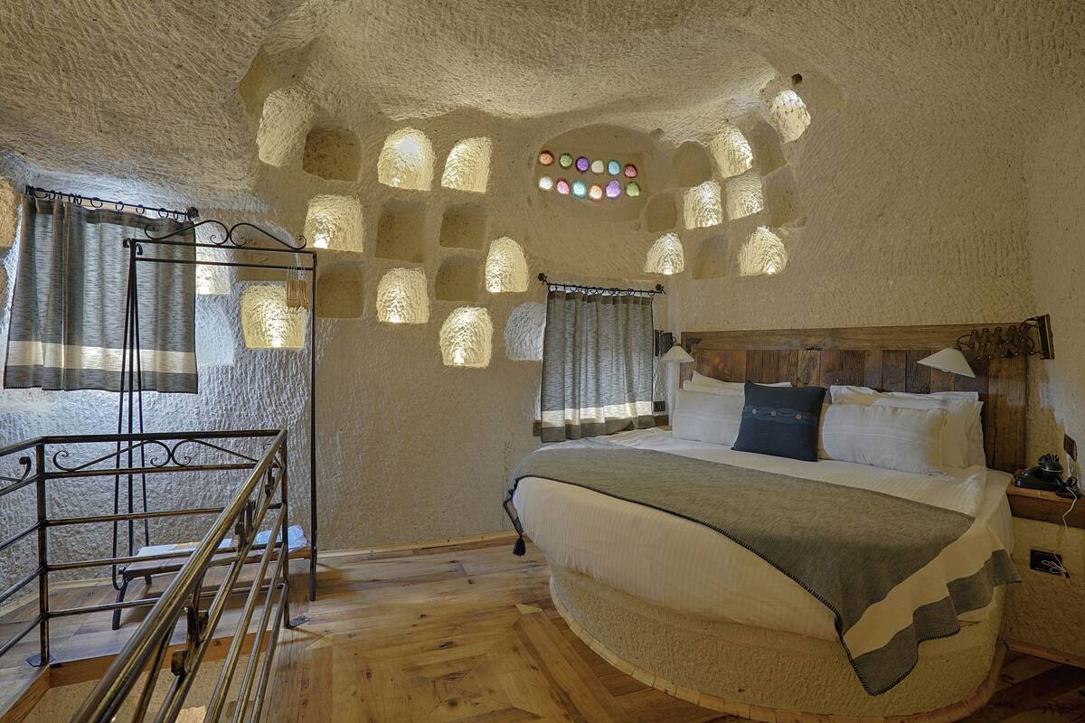 Una camera da letto con un letto in legno, una scala in metallo e pareti in pietra.