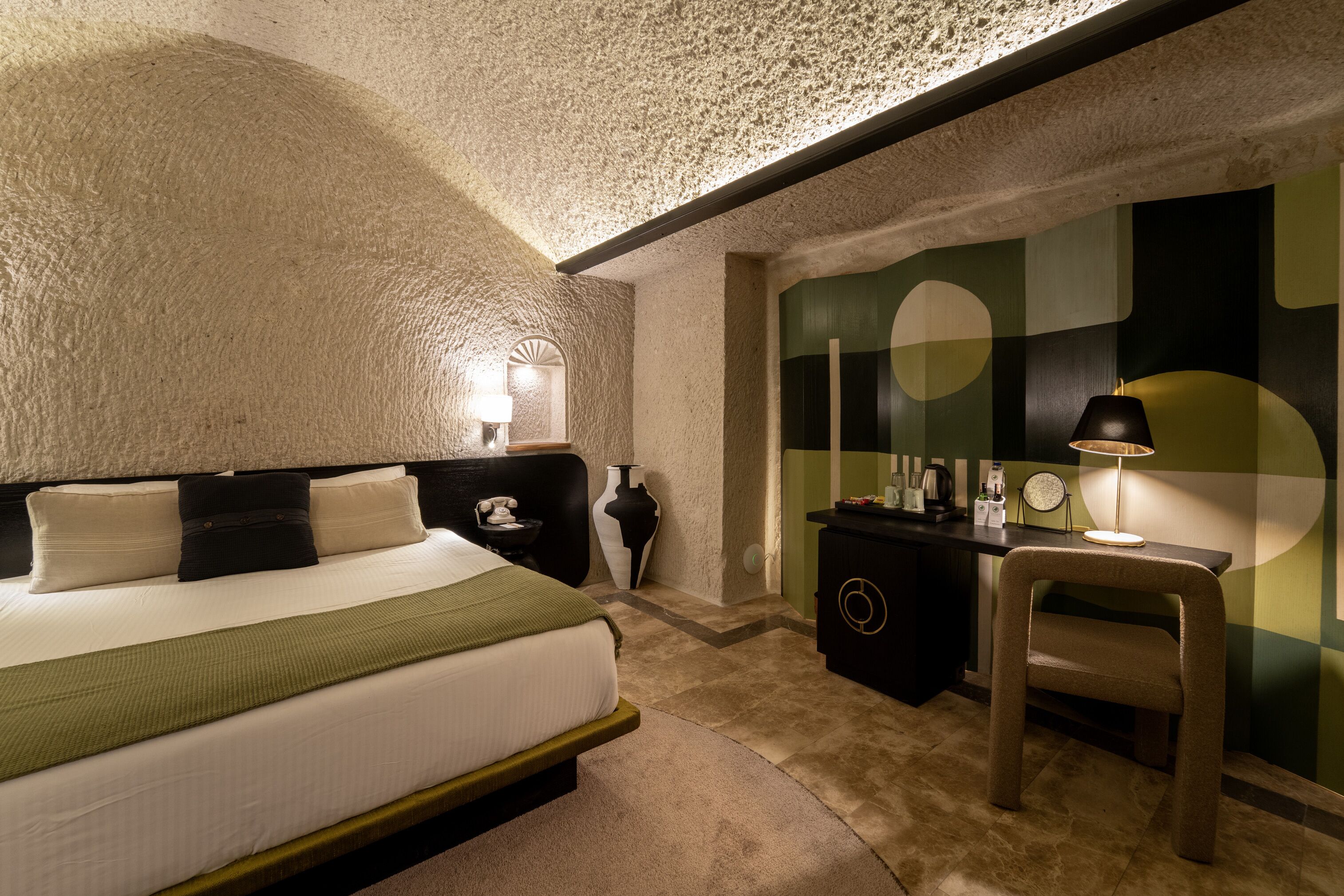A bedroom with a bed, bedside table, lamp, and a dresser.
