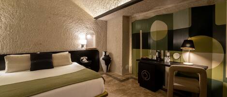 A bedroom with a bed, bedside table, lamp, and a dresser.