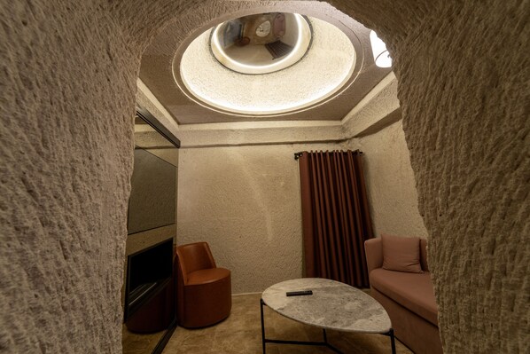 Una habitación acogedora con un tragaluz circular, un sofá, una mesita redonda y una silla.