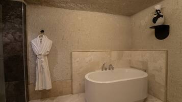 Een moderne badkamer met een vrijstaand bad, een badjas hangend aan de muur en een handdoekrek.