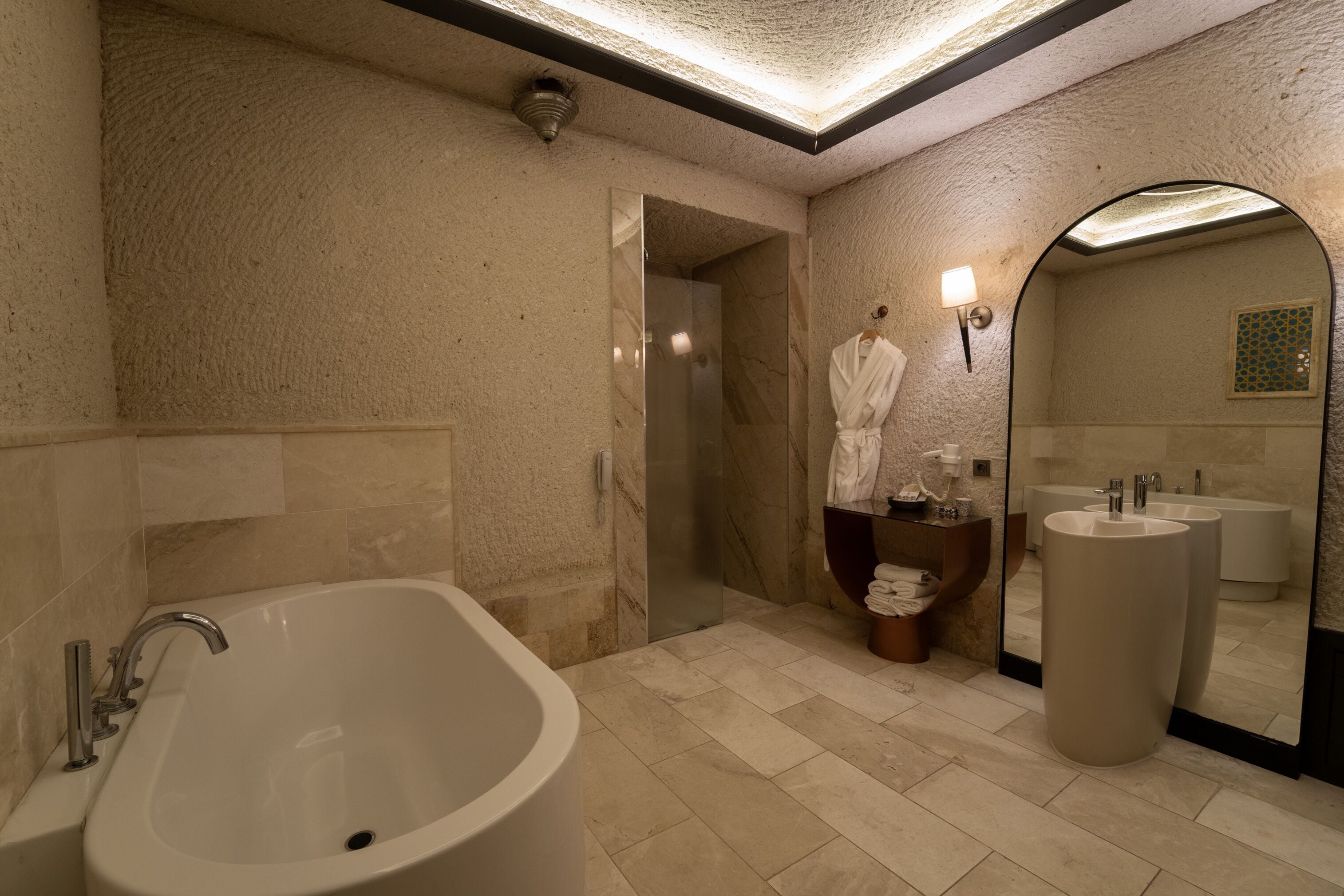 Un baño moderno con una bañera independiente, un espejo grande y un tocador doble.