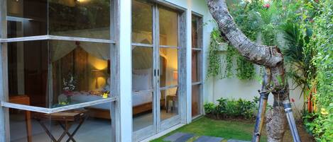 A modern house with large glass windows, a small garden, and a tree.