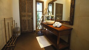 A bathroom with a wooden vanity, a large mirror, and a towel rack. - The Decks Bali (Legian)