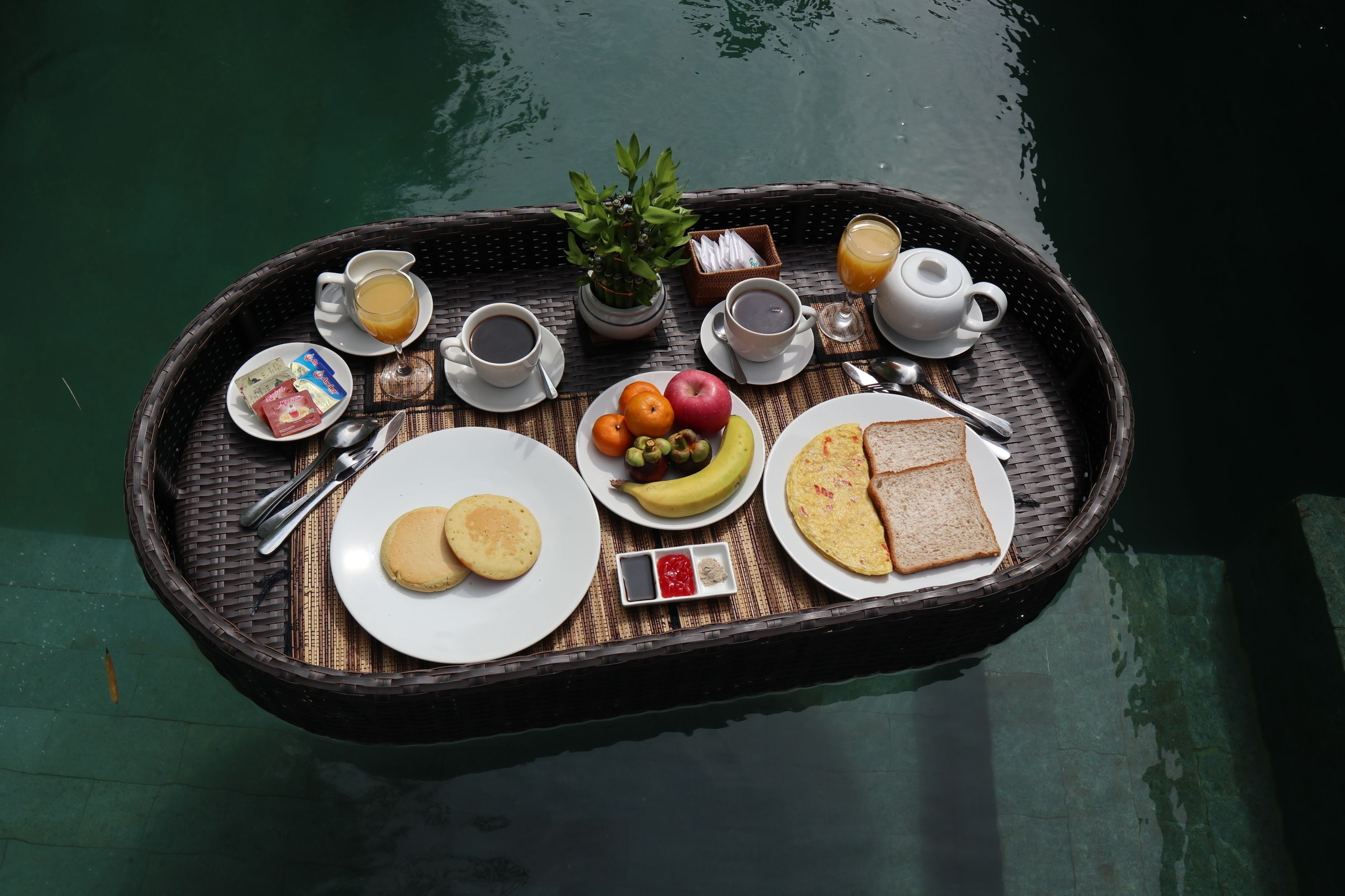A breakfast tray with eggs, toast, fruit, and beverages on a boat.