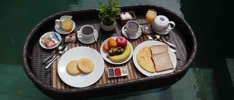 A breakfast tray with eggs, toast, fruit, and beverages on a boat.