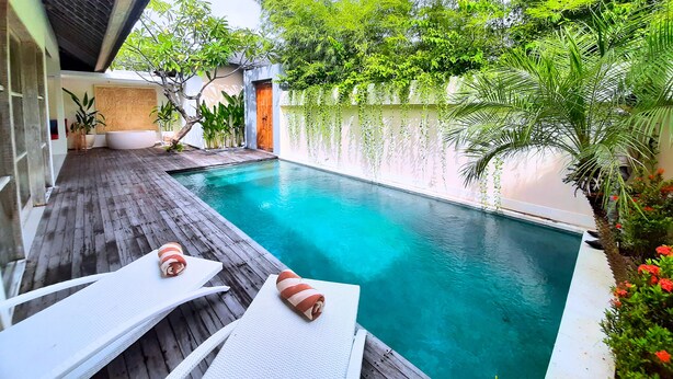 A pool area with wooden decking, two lounge chairs, and a small pool. - The Decks Bali (Legian)