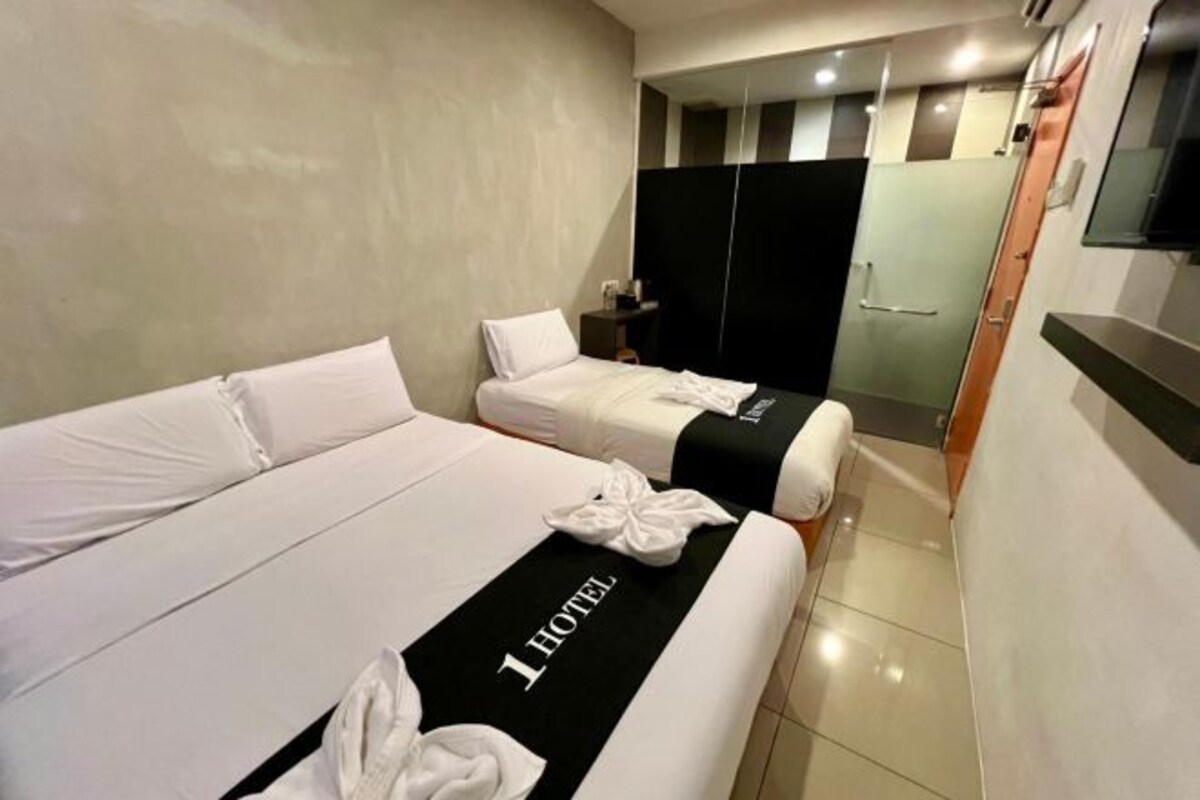 Una habitación de hotel con dos camas, una colcha blanco y negro, y un cartel que dice '1 HOTEL'.