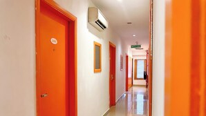 Un pasillo con puertas anaranjadas, suelo de baldosas y un cartel que indica el camino hacia el gimnasio.