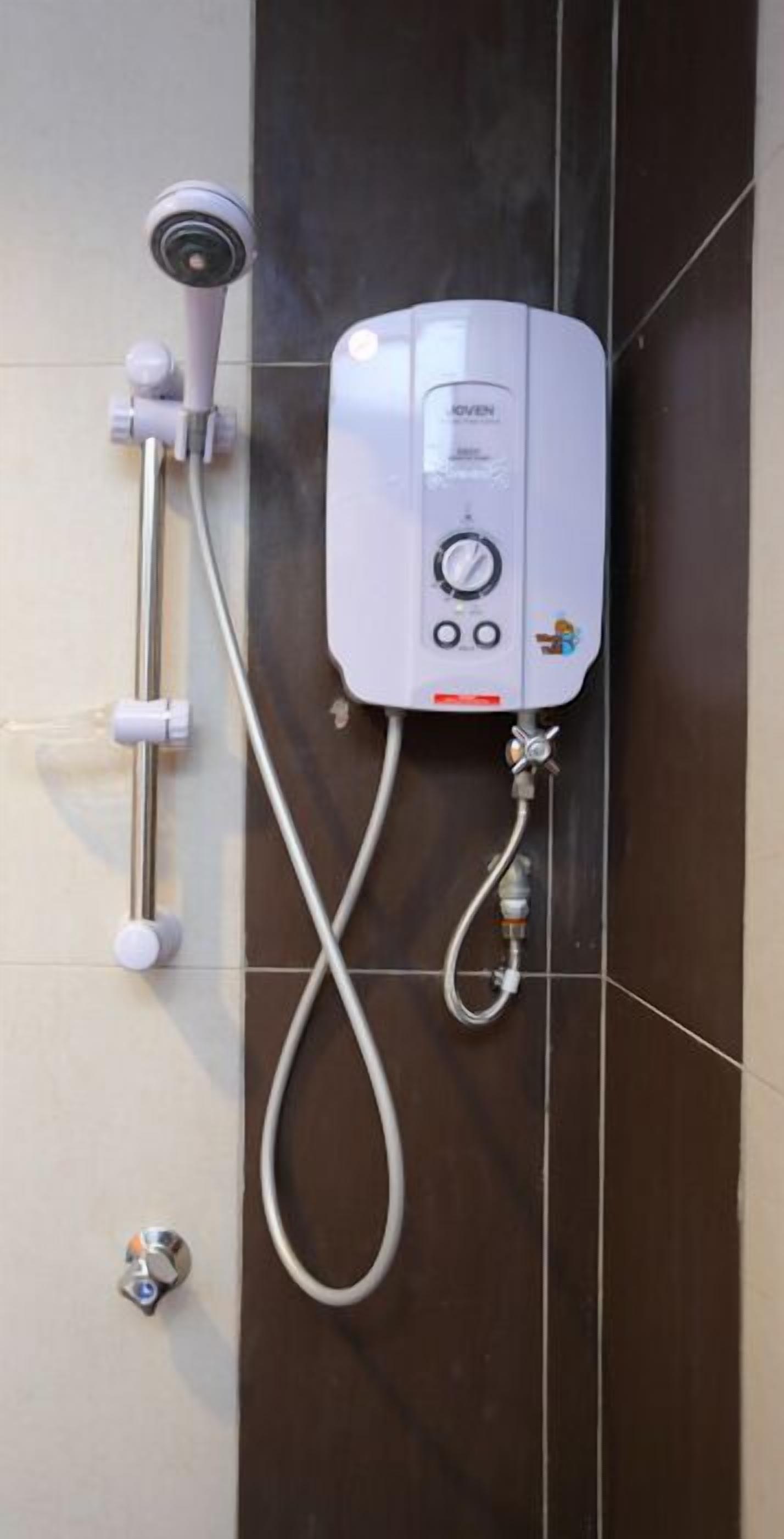 Chuveiro fixado na parede com painel de controle, chuveiro manual e mangueira flexível.