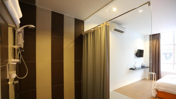 Una habitación de hotel moderna con ducha, cama, una mesita y televisor.