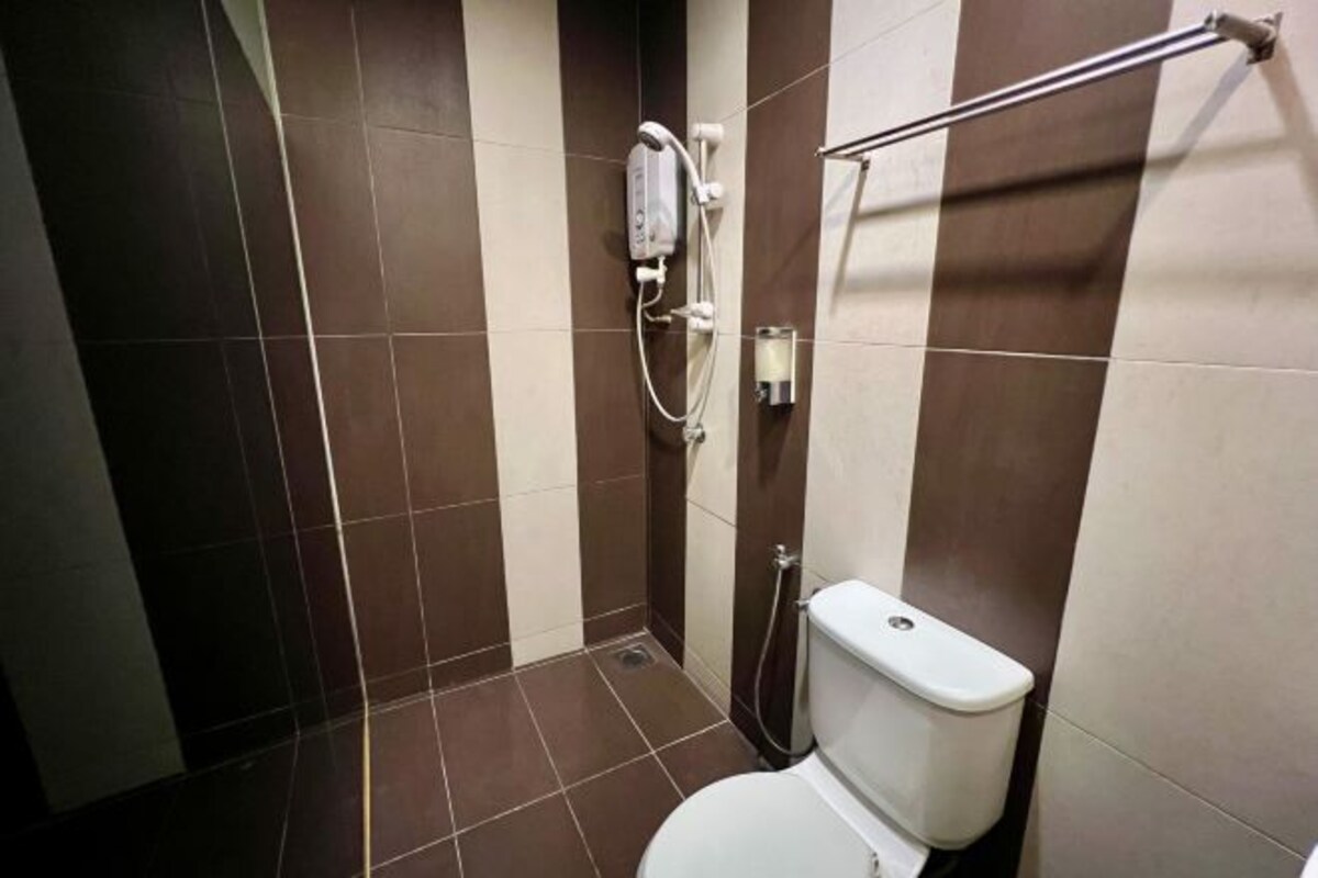 Un baño con inodoro, ducha y paredes de azulejos.