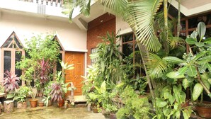 A courtyard with various potted plants, a wooden door, and a brick wall. - Kaung Lay Inn (Yangon)