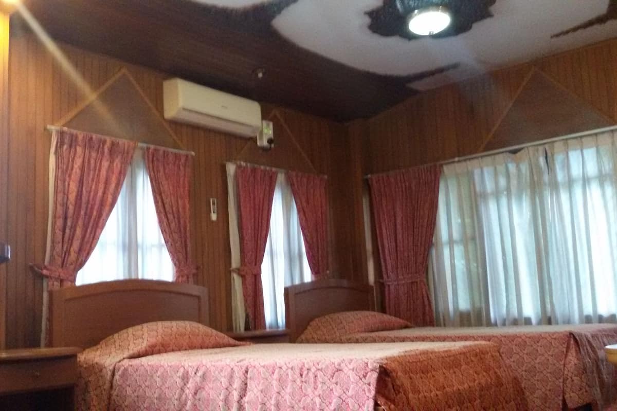 A room with two beds, wooden walls, and a ceiling fan.