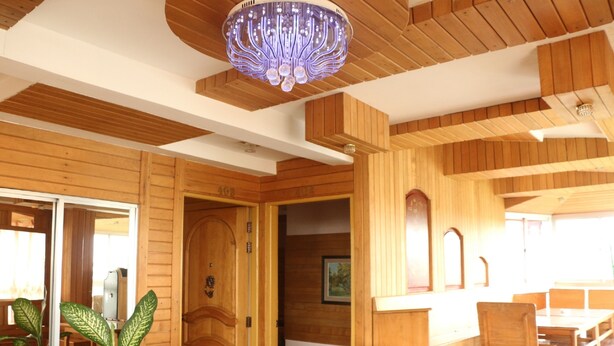 A wooden interior with a chandelier, wooden walls, and a dining area with tables and chairs. - Kaung Lay Inn (Yangon)