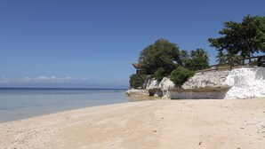 Une plage avec une structure en bois construite sur une falaise, d’où l’on a une vue sur la mer.