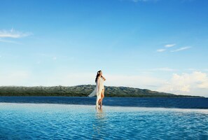 Una piscina al aire libre, una piscina infinita, sombrillas