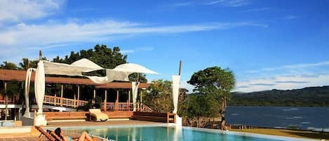 Een buitenzwembad, een infinity pool, parasols voor strand/zwembad