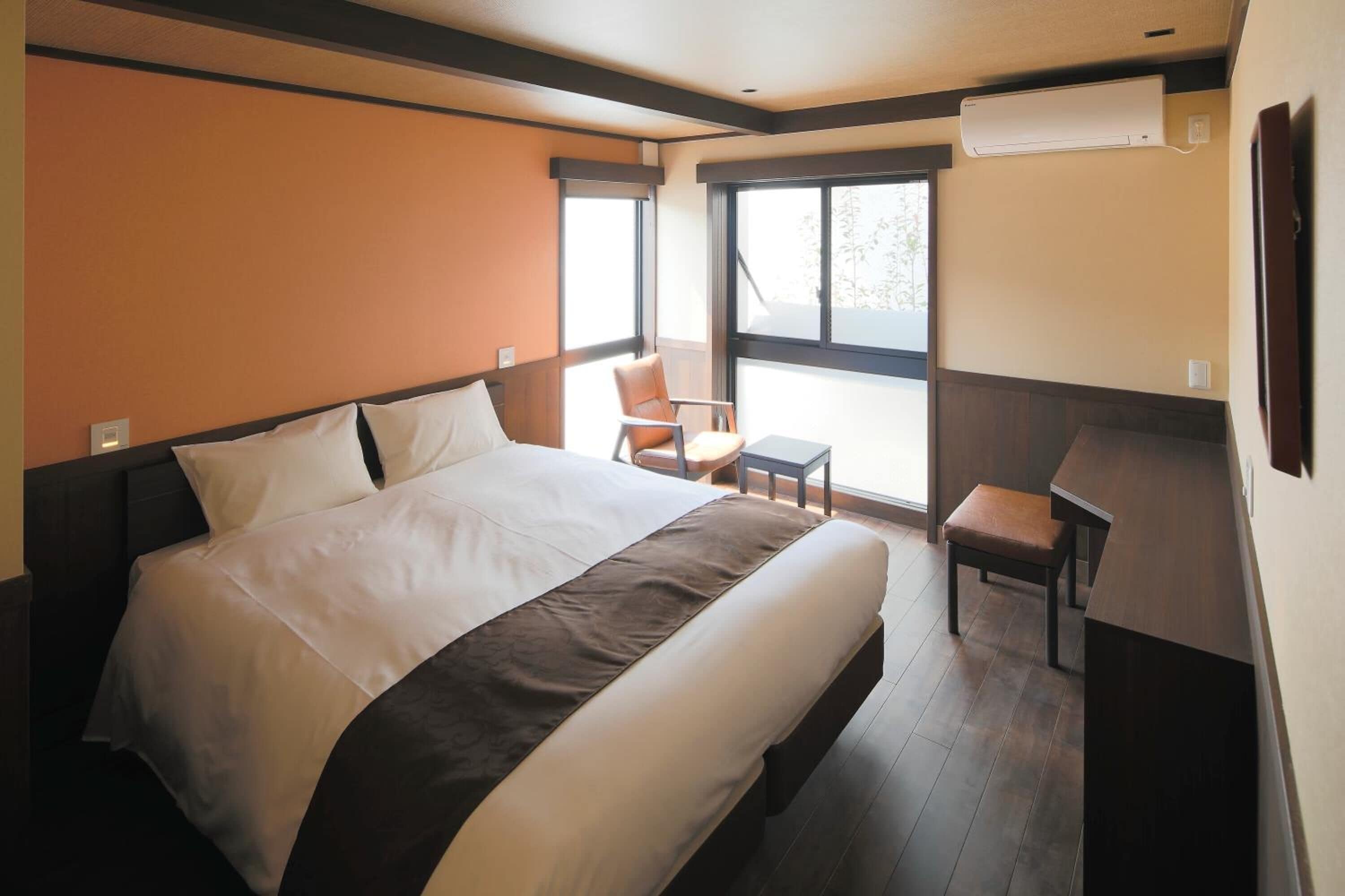 Habitación de hotel con una cama grande, una mesita, una silla y ventana con vistas.