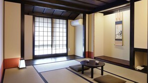 A traditional tatami mat room with a tatami mat table, cushions, and a shoji screen door.
