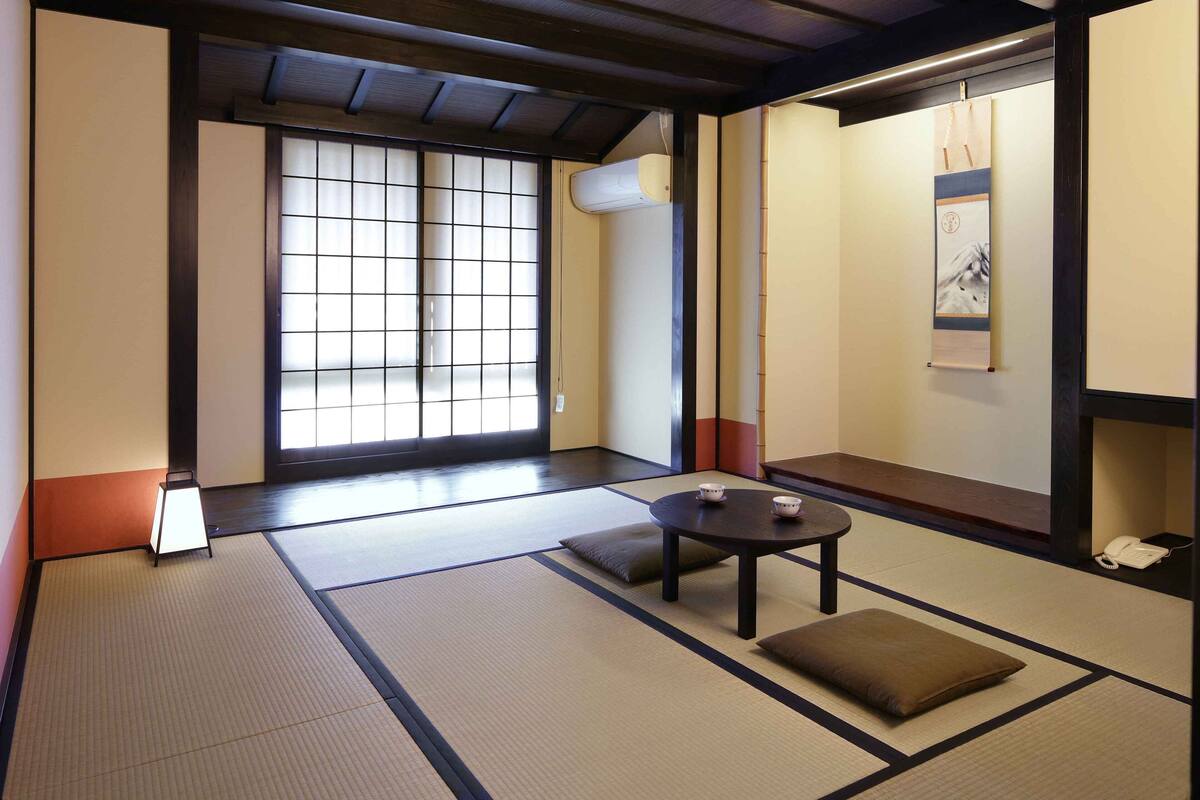 Una stanza tradizionale con tatami, un tavolo in tatami, cuscini e una porta scorrevole shoji.