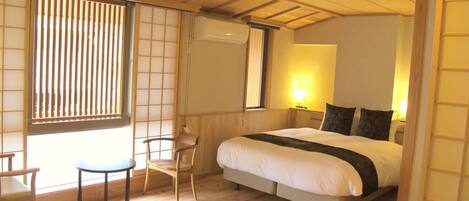 A traditional Japanese-style bedroom with a bed, a chair, and a window with blinds.