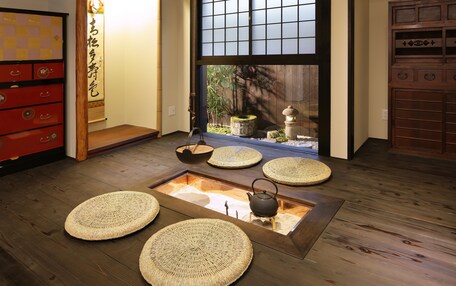 A traditional Japanese room with tatami flooring, a shoji screen, and a tatami mat in the center.
