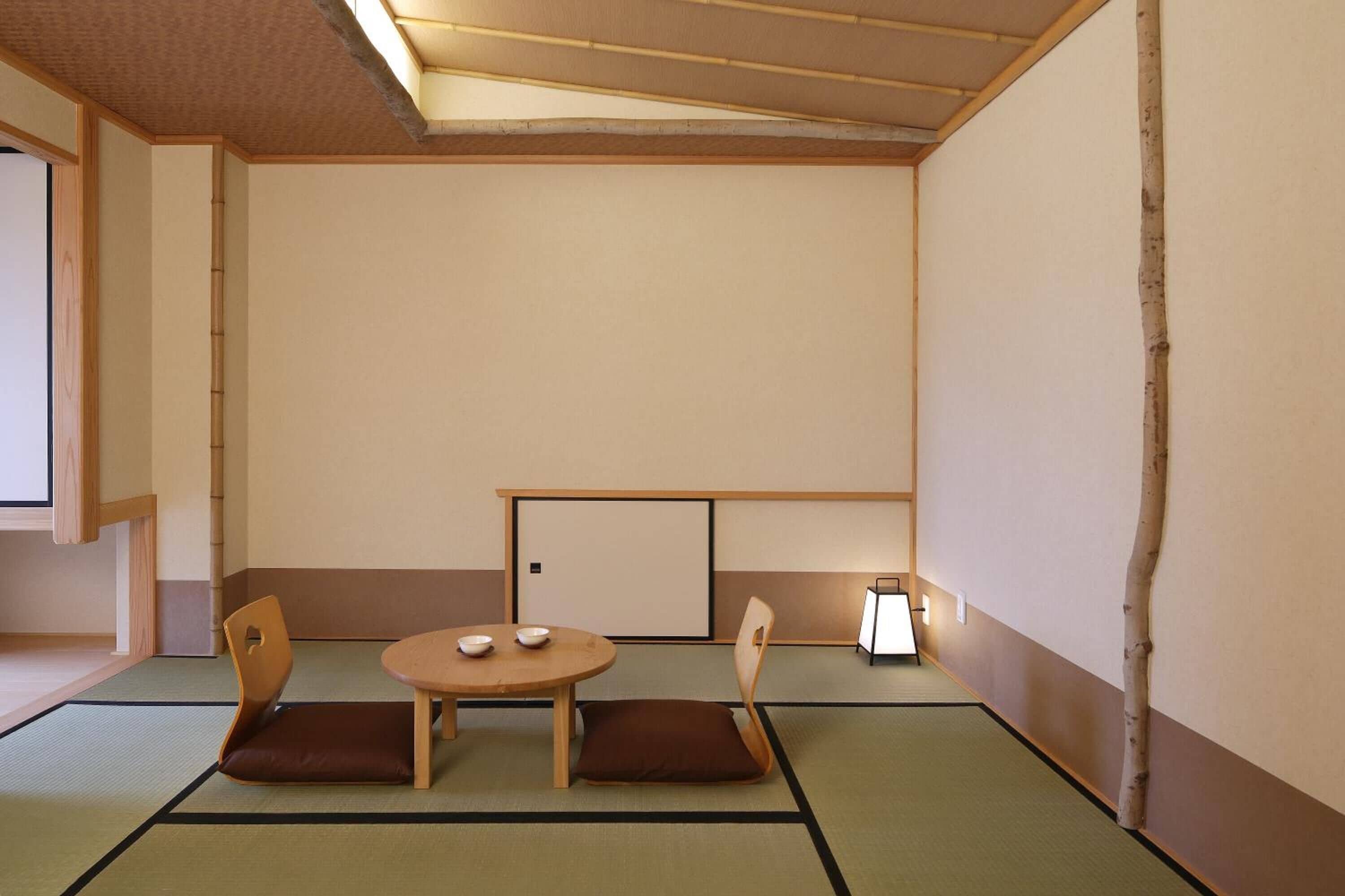 Um quarto japonês tradicional com tatame, uma mesa baixa com almofadas e uma porta deslizante.