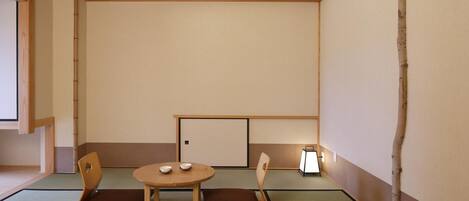 Um quarto japonês tradicional com tatame, uma mesa baixa com almofadas e uma porta deslizante.