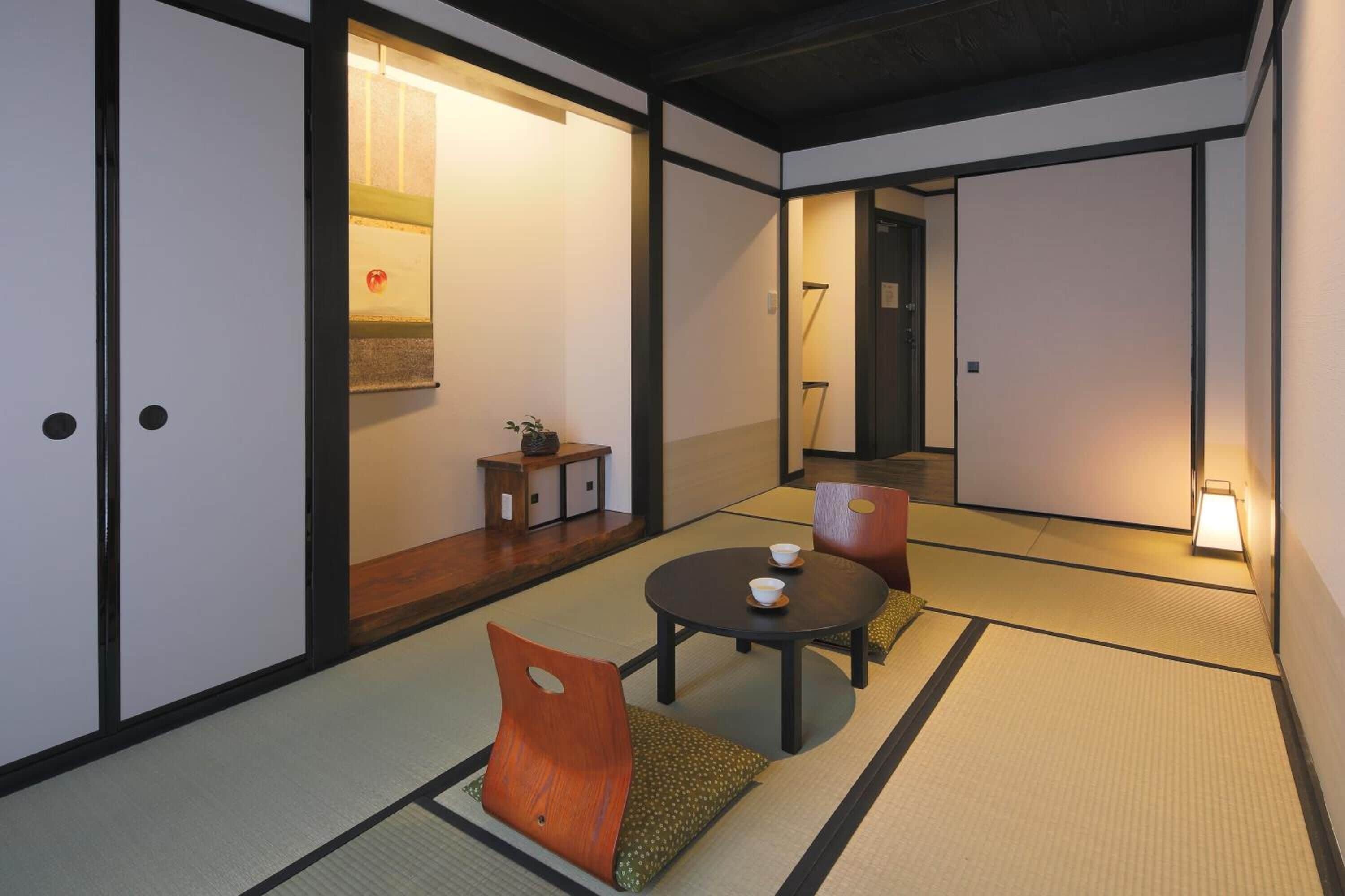 Une pièce de style japonais traditionnel, avec un sol recouvert de tatamis, une petite table et une tasse, ainsi qu’un coussin.
