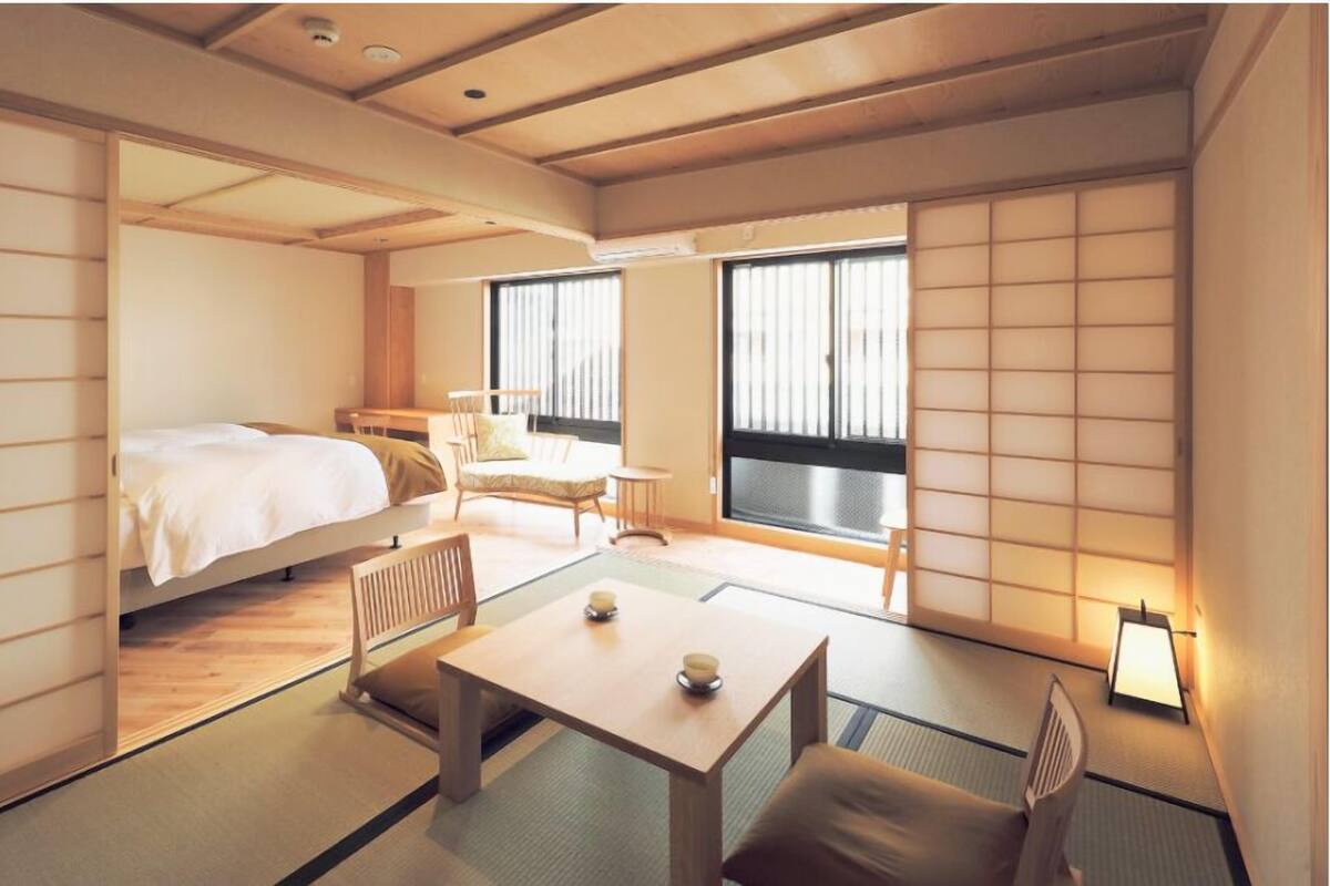 Una tradizionale stanza in stile giapponese, con pavimento in tatami, un letto basso, un tavolino con un set da tè e porte scorrevoli.