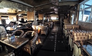 Ein luxuriöses Restaurant mit hochgelehnten Ledersesseln, einem polierten Marmorboden und einer Bar mit einem großen Spiegel und Barhocker.
