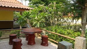 Un patio al aire libre con una mesa redonda de madera y cuatro taburetes a juego.