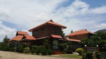 A two-story building with a red-tiled roof, a welcome sign, and a garden sign.