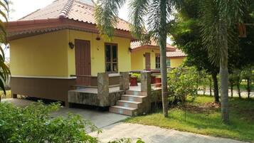 A yellow building with a tiled roof and a stone staircase leading to a door.