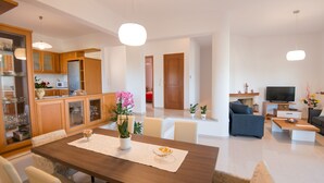 A modern living room with a wooden dining table, a sofa, and a TV. - Diogenis Home (Rethymno)