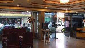 Een hotel lobby met een receptiebalie, een zithoek en een televisie.