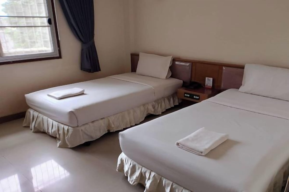 A hotel room with two beds, a nightstand, and a window with curtains.