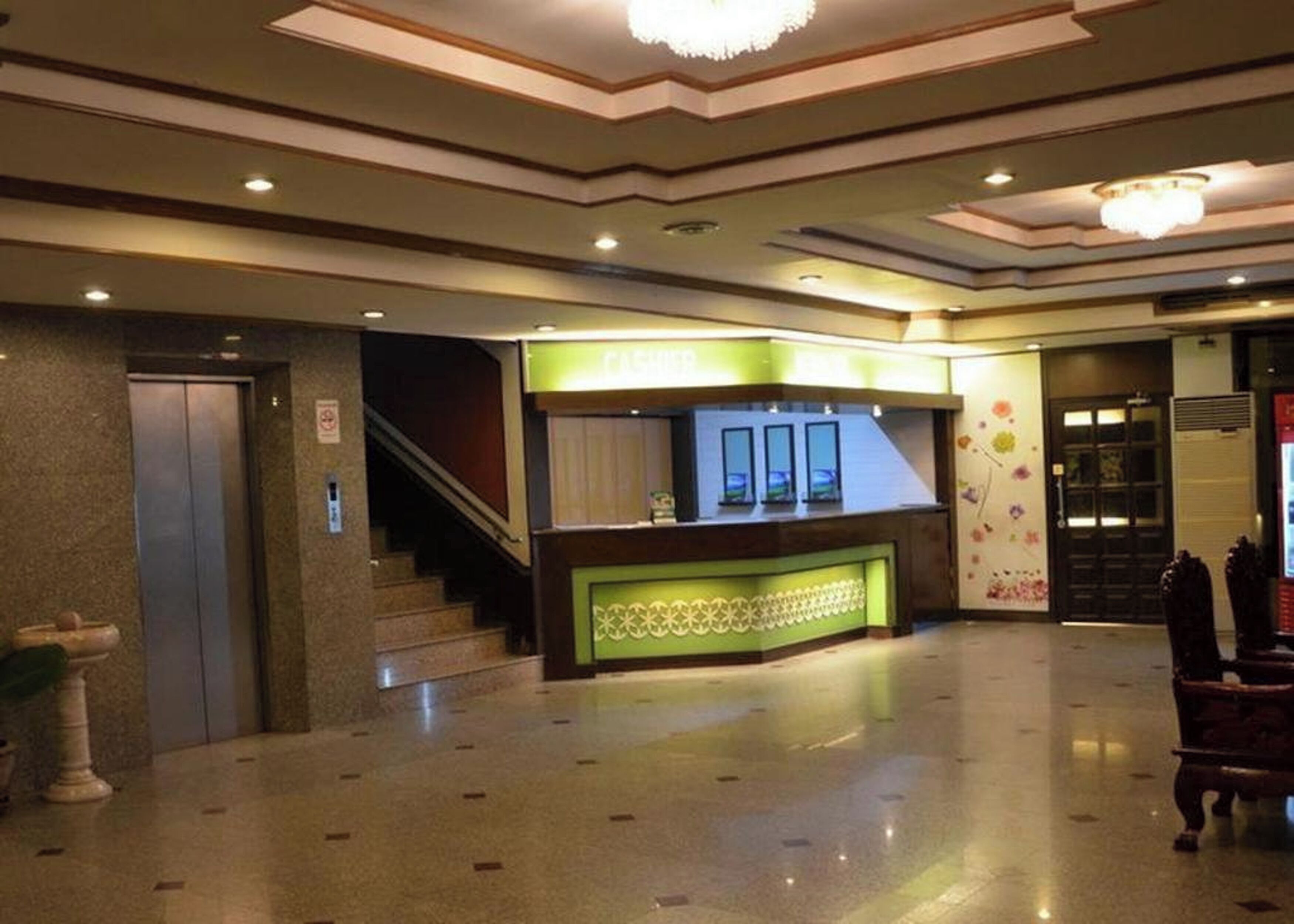 A hotel lobby with a reception desk, a staircase, and a door.