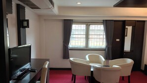 Een hotelkamer met een flatscreen televisie, een bureau en twee stoelen.