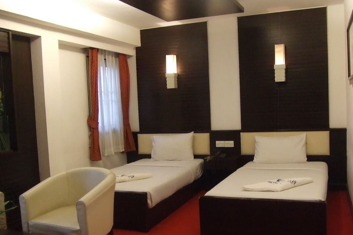 A hotel room with two beds, a chair, and a desk.