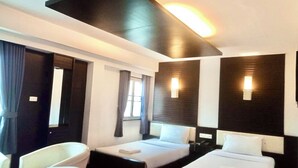 Een hotelkamer met twee bedden, een bureau, een stoel en een groot raam.