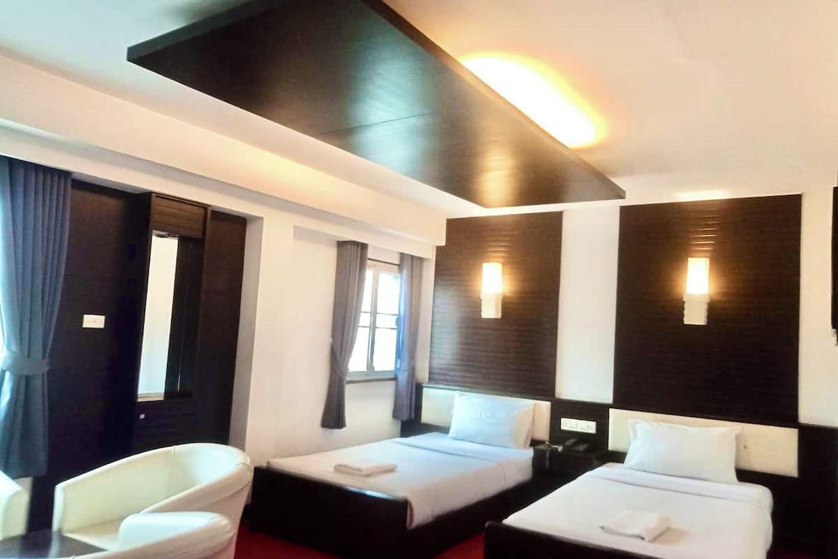 A hotel room with two beds, a desk, a chair, and a large window.